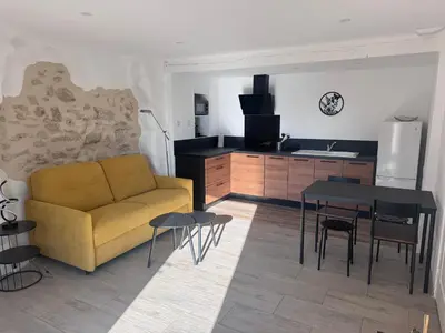 a living room with a yellow couch and a kitchen at Studio Rénové de Charme en Provence in Caumont-sur-Durance