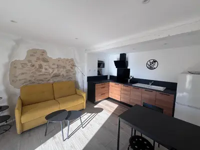 a living room with a couch and a kitchen at Studio Rénové de Charme en Provence in Caumont-sur-Durance