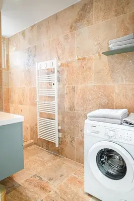 a washing machine in a bathroom with a tile wall at L Appartement 1 Chambre - Gîte la Bergerie du Ventoux in Mormoiron