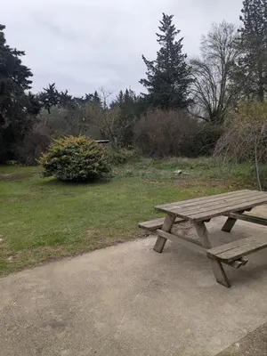 a wooden picnic table sitting next to a field at Le gîte du domaine de Sinaca Villa in Sénas