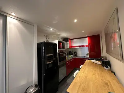 a kitchen with a black refrigerator and a wooden table at Chez Anne - Appartement cosy avec mezzanine au cœur du centre historique d'Aix-en-Provence in Aix-en-Provence