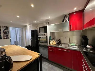 a kitchen with red cabinets and a wooden counter top at Chez Anne - Appartement cosy avec mezzanine au cœur du centre historique d'Aix-en-Provence in Aix-en-Provence