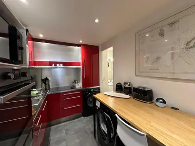 a kitchen with red cabinets and a wooden counter top at Chez Anne - Appartement cosy avec mezzanine au cœur du centre historique d'Aix-en-Provence in Aix-en-Provence