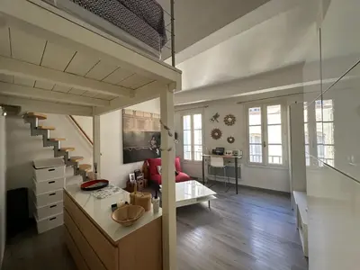 a living room with a staircase and a red couch at Chez Anne - Appartement cosy avec mezzanine au cœur du centre historique d'Aix-en-Provence in Aix-en-Provence