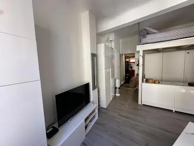 a living room with a flat screen tv on a white wall at Chez Anne - Appartement cosy avec mezzanine au cœur du centre historique d'Aix-en-Provence in Aix-en-Provence