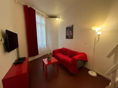 a living room with a red couch and a tv at Joli appartement atypique dans le centre d'Aix in Aix-en-Provence
