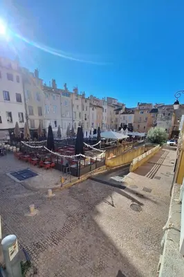 a group of tables with umbrellas and chairs and buildings at Grand studio dans le centre historique in Aix-en-Provence