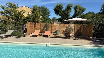 a pool with chairs and an umbrella next to a fence at Les Oliviers- Bed and Breakfast in Velleron
