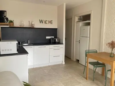 a kitchen with white cabinets and a table and a refrigerator at Les Oliviers- Bed and Breakfast in Velleron