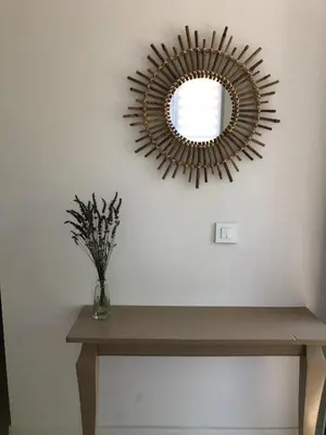 a mirror on a wall with a vase on a table at Les Oliviers- Bed and Breakfast in Velleron