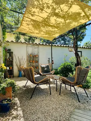 a patio with three chairs and a table and a yellow umbrella at Havre de paix proche centre ville, jardin, piscine in LʼIsle-sur-la-Sorgue