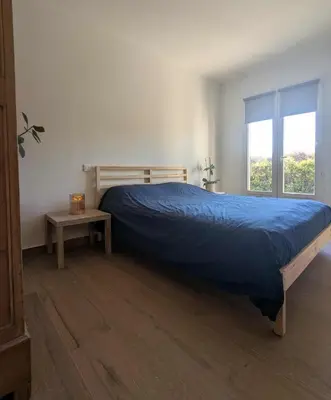 a bedroom with a bed with a blue bedspread and a table at Villa Papillon in Monteux