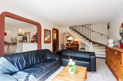 a living room with a black leather couch and a table at Les gites de Bel-Air en Luberon in Les Taillades