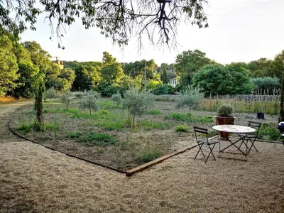 a picnic table and chairs in a garden at Petit mas en Provence in Cornillon-Confoux