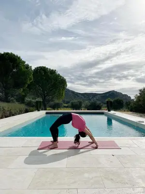 a woman doing a yoga pose in front of a pool at La Villa des Glauges in Eyguières