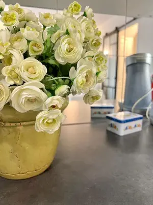 a yellow vase filled with white roses on a counter at La Bastide du Golfeur, Jardin et Piscine in Mallemort