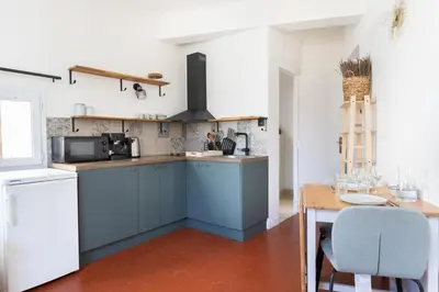 a kitchen with blue cabinets and a wooden table at Modern studio Le Renoir - Center of city - WiFi in Aix-en-Provence