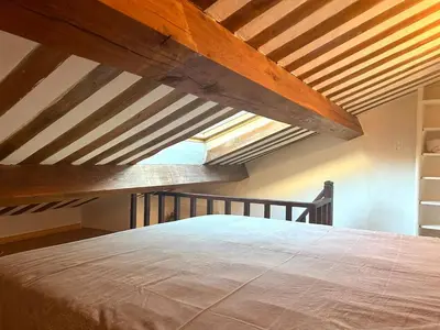 a large bed in a room with wooden ceilings at Charmante maison de village avec clim et parking à proximité d'Aix-en-Provence in Éguilles