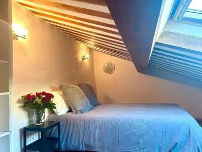 a bedroom with a bed and a vase of flowers on a table at Charmante maison de village avec clim et parking à proximité d'Aix-en-Provence in Éguilles