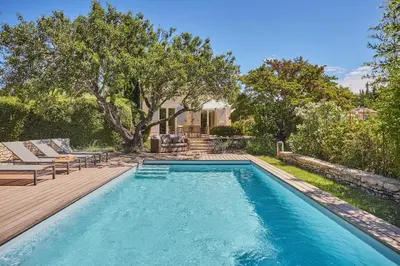 a swimming pool in a backyard with a deck and trees at La Paulanne in Bonnieux