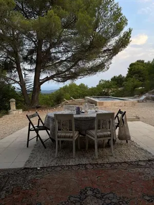 a table and chairs on a patio with a tree at Luberon house with view in Cucuron