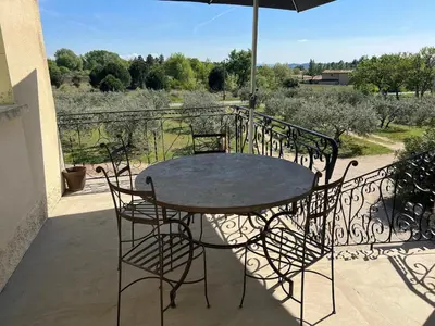 a table and chairs on a balcony with an umbrella at Le gîte des granges in Bédoin