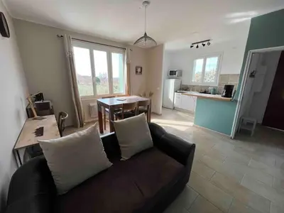 a living room with a couch and a kitchen at Le gîte des granges in Bédoin