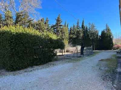 a person is standing next to a fence at Le gîte des granges in Bédoin