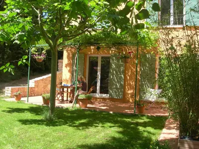 a house with a garden and a person sitting at a table at Holiday House Teulon in Éguilles