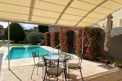 a patio with a table and chairs next to a pool at Family villa with garden and pool in LʼIsle-sur-la-Sorgue