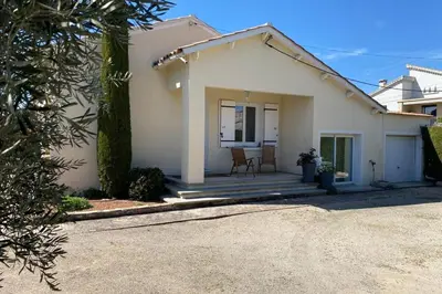 a white house with a porch with a table and chairs at Family villa with garden and pool in LʼIsle-sur-la-Sorgue