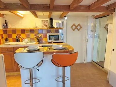 a kitchen with two bar stools and a counter at L'essentiel - Studio cosy au cœur du centre ville historique d'Aix-en-Provence in Aix-en-Provence