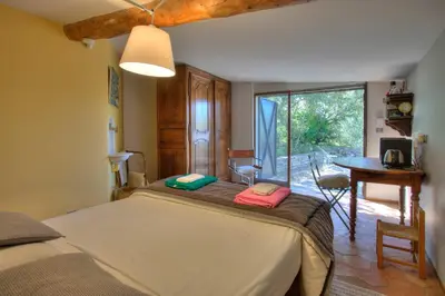 a bedroom with a bed and a table and a window at Bergerie provencale, 4 personnes, piscine in Gordes