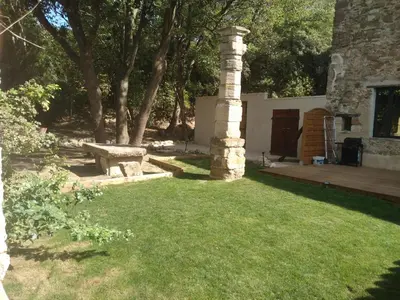 a garden with a stone pillar and a bench at Les feuillets de la Buire in Monteux