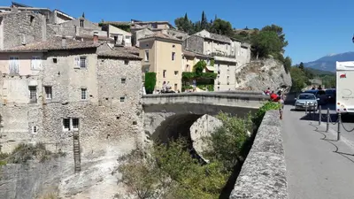 a bridge over a road in a town with buildings at Ventoux gîtes - appartements typiques avec vue sur le Mont Ventoux in Caromb