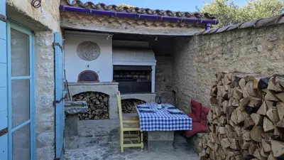 a patio with a table and a pizza oven at Ventoux gîtes - appartements typiques avec vue sur le Mont Ventoux in Caromb