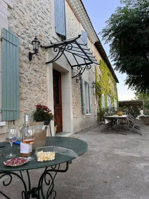 a table in front of a stone building with a table with wine glasses at Farm House, 10 min d'Avignon in Jonquerettes