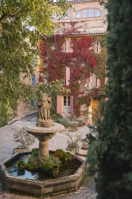 a fountain in the middle of a courtyard with a building at Auberge du Presbytère in Saignon