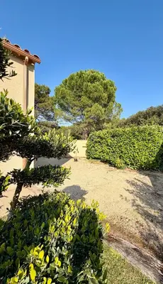 a garden with green bushes and a building and trees at Farniente à Valloncourt in Cheval-Blanc