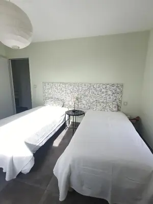 a white bedroom with two beds and a table at Villa ChloLéa in Caromb