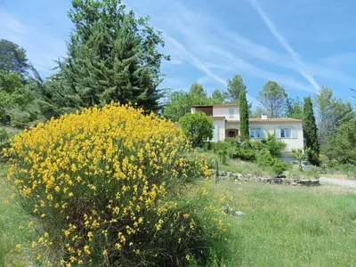 a field of yellow flowers in front of a house at Holiday Home Charmantes Landhaus mit Garten by Interhome in Pierrevert