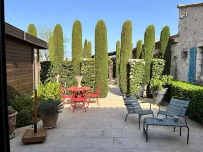 a patio with a red table and chairs and bushes at Holiday Home Das Atelier im Mas Naste by Interhome in Eygalières