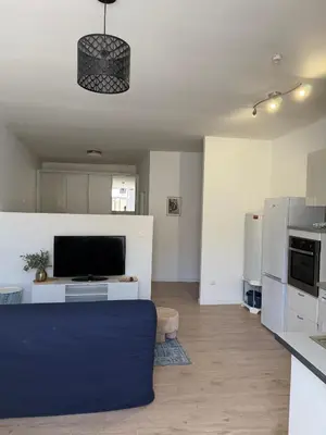 a living room with a blue couch and a kitchen at La Casa Grans - Charme et calme en Provence in Grans