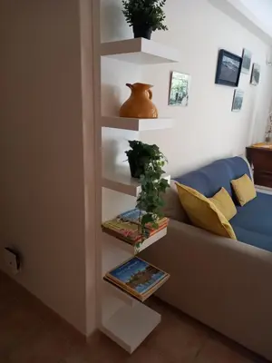 a living room with a couch and a shelf with books at Hébergement tout confort au pied du Luberon in Cabrières-dʼAigues