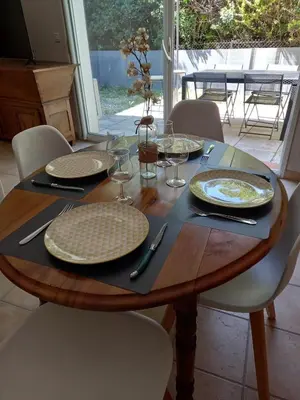 a wooden table with plates and wine glasses on it at Hébergement tout confort au pied du Luberon in Cabrières-dʼAigues