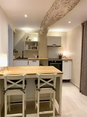 a kitchen with a wooden table and two stools at L' Ecrevisse in LʼIsle-sur-la-Sorgue