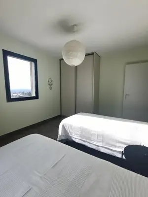 a white bedroom with two beds and a window at ChloLéa in Caromb