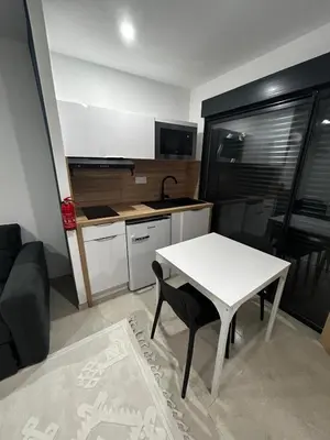 a small kitchen with a white table and a table and chairs at Studio 2 personnes maximum in Saint-Andiol
