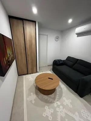 a living room with a black couch and a wooden table at Studio 2 personnes maximum in Saint-Andiol