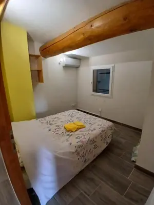 a bedroom with a bed with a yellow shirt on it at Luberon Sud in La Tour-dʼAigues